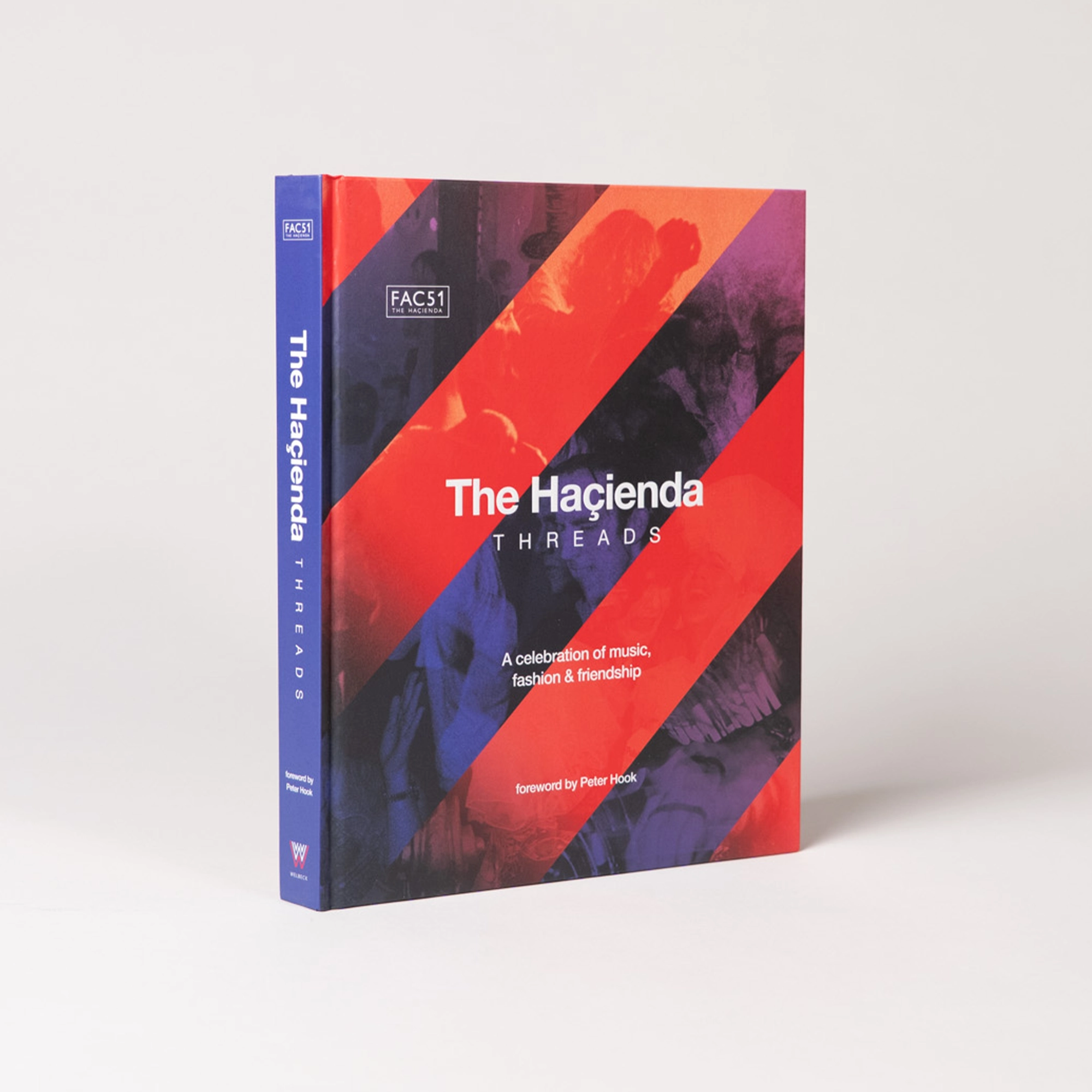 The Hacienda: Threads, standing on a grey background, showing off blue spine and red striped cover.